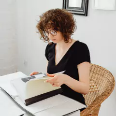 a woman sitting at a desk reading a book