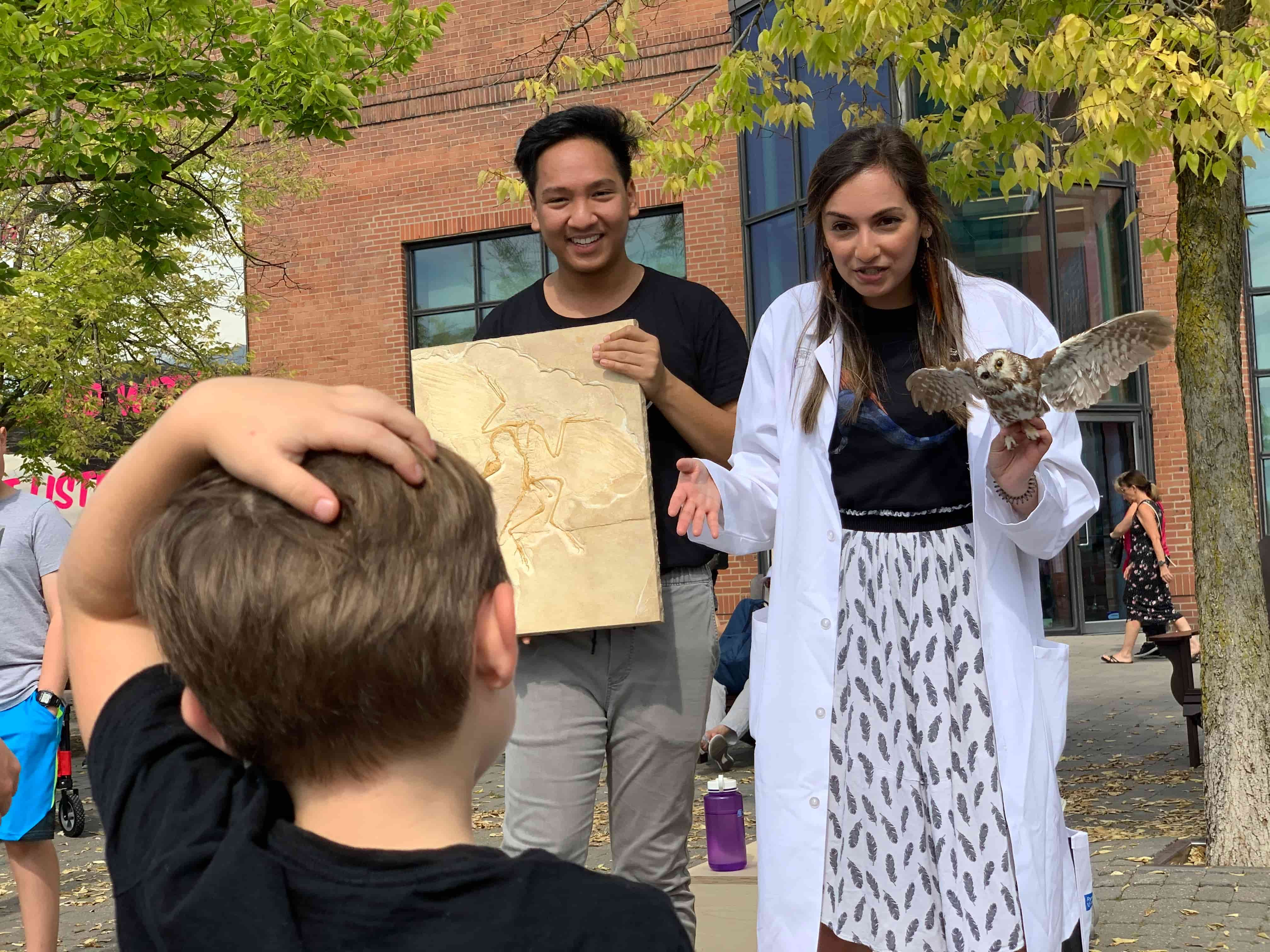 a woman holding an owl and a boy looking at a map