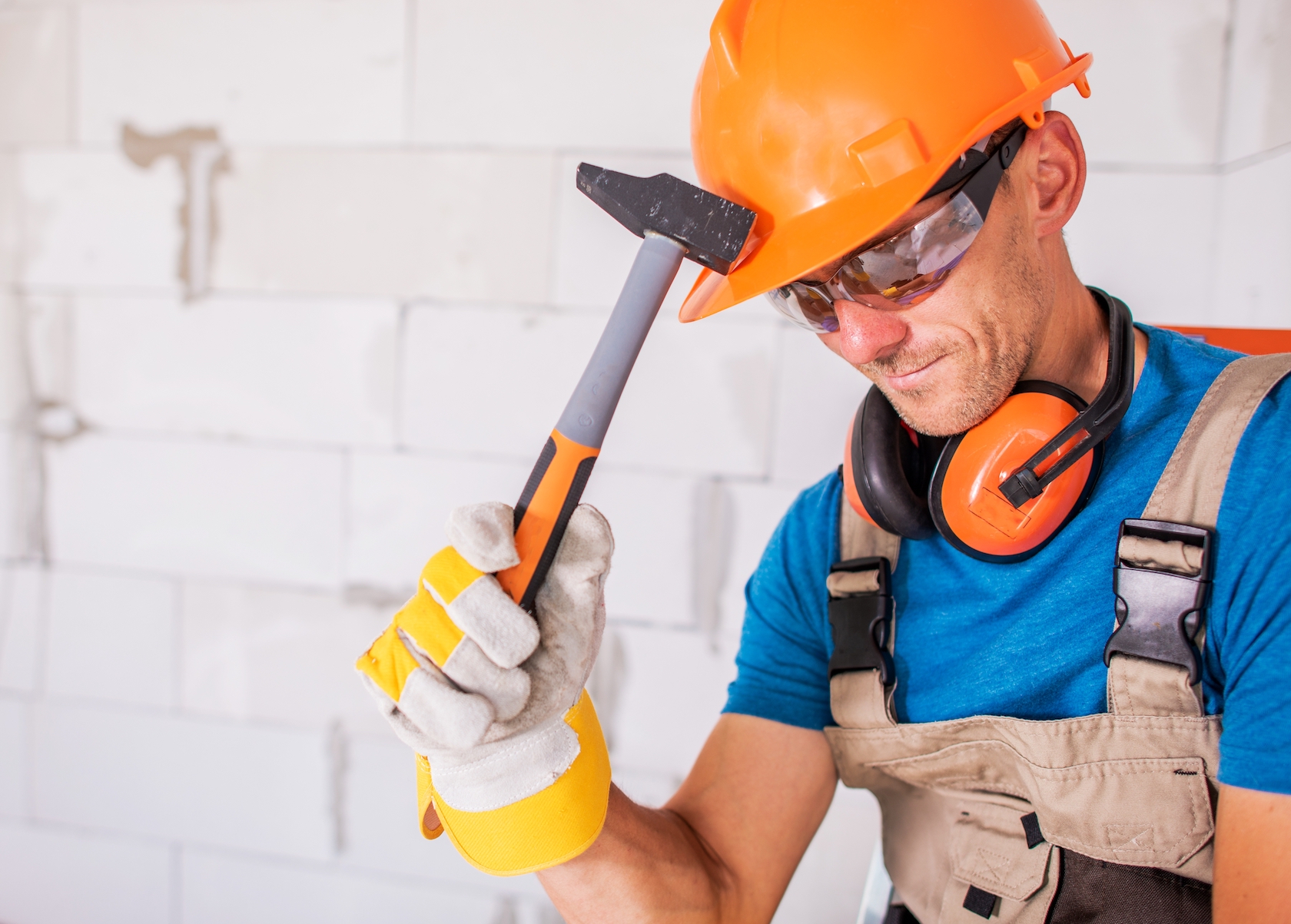 a man wearing a hard hat and gloves holding a hammer