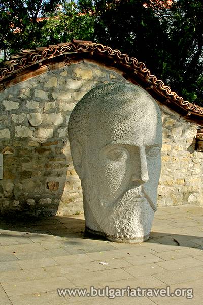a stone head sculpture in front of a stone building
