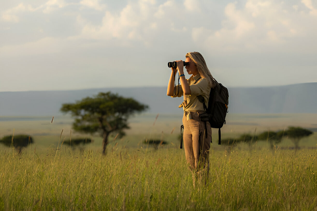 a woman looking through binoculars in a field