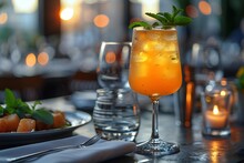 a glass of orange liquid with mint leaves on top of a table