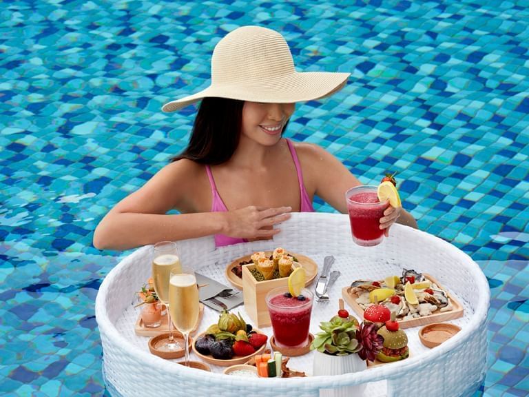 a woman in a pool with a table full of food
