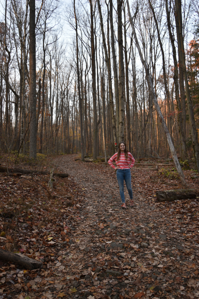 a woman standing on a path in the woods