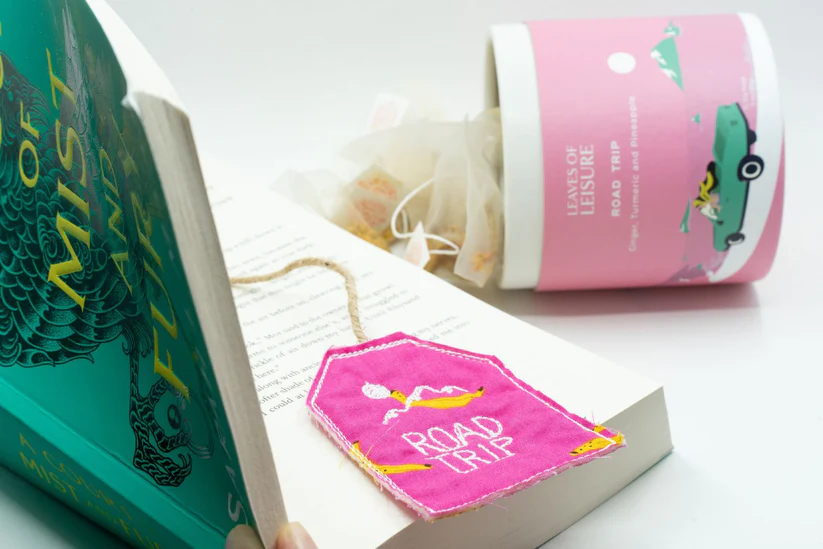 a book with a pink tag on it next to a cup of tea