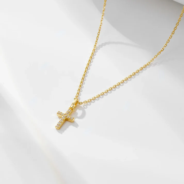 a gold cross necklace on a white surface