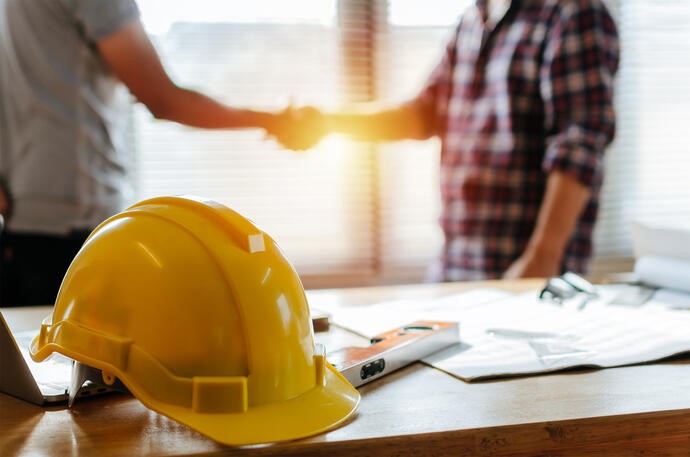 a yellow hard hat on a table with a man shaking hands
