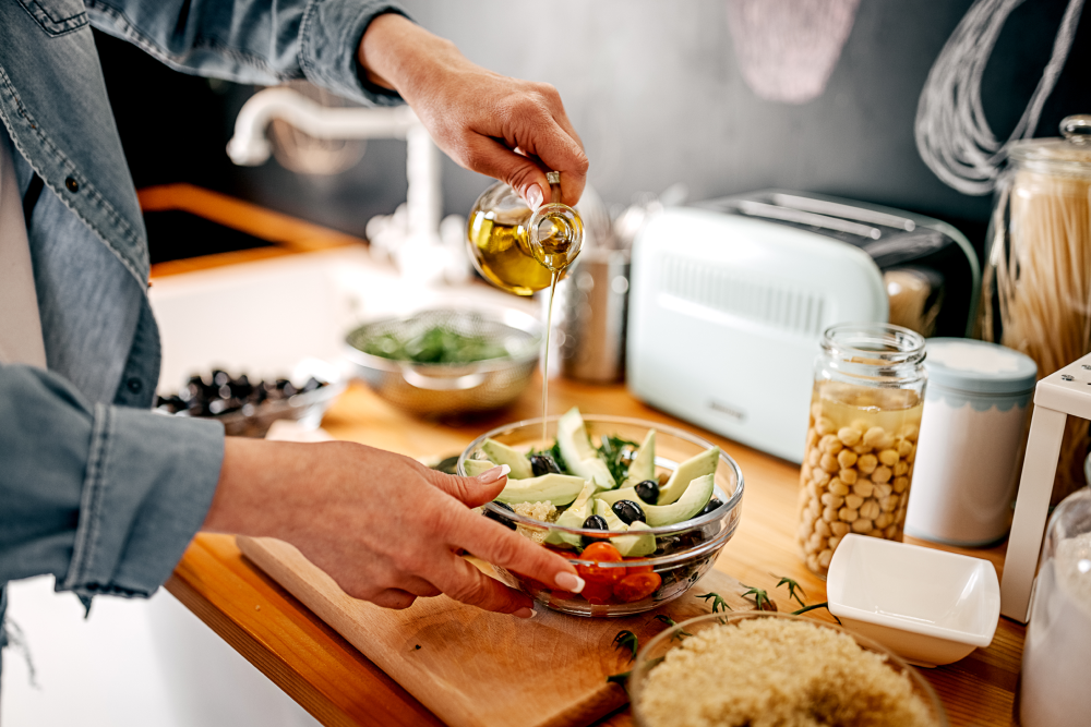 a person pouring olive oil into a bowl of food