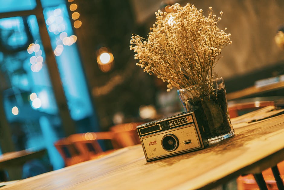 a camera and a vase of flowers on a table