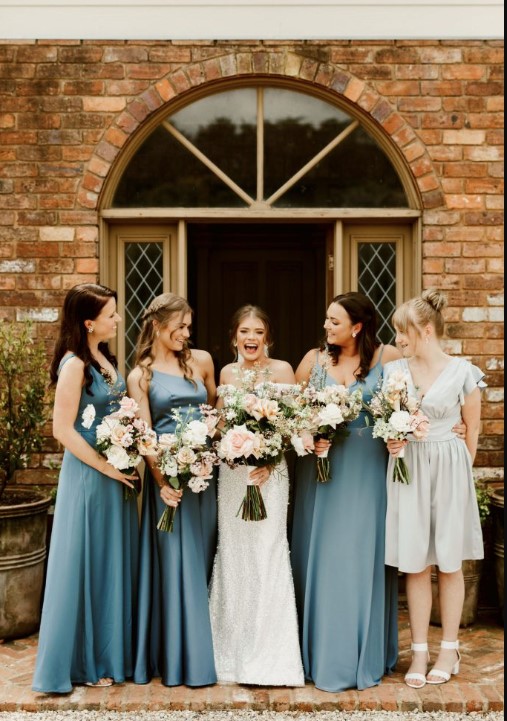 a group of women in blue dresses holding flowers