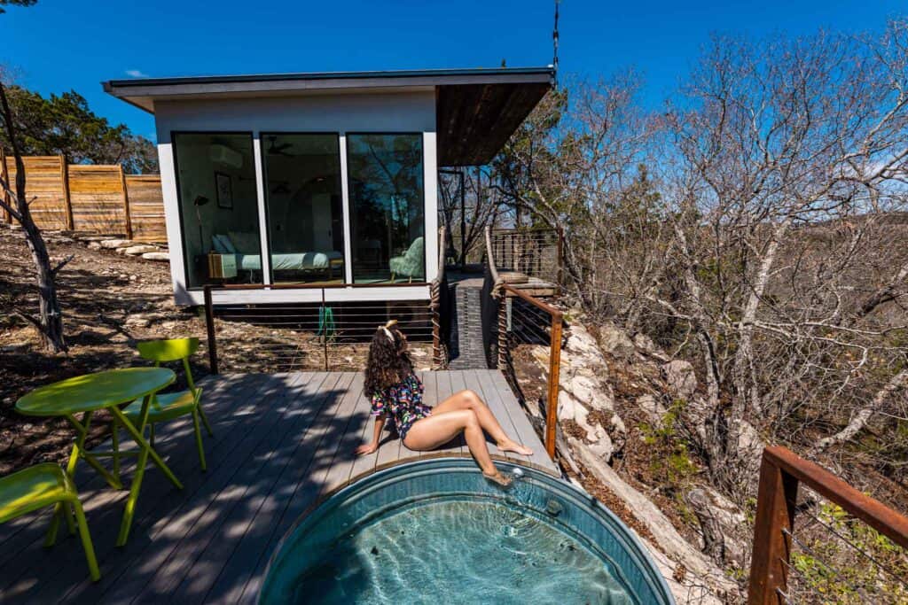 a woman sitting on a deck with a hot tub in the background