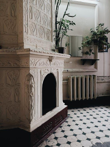a white fireplace with a plant in the corner