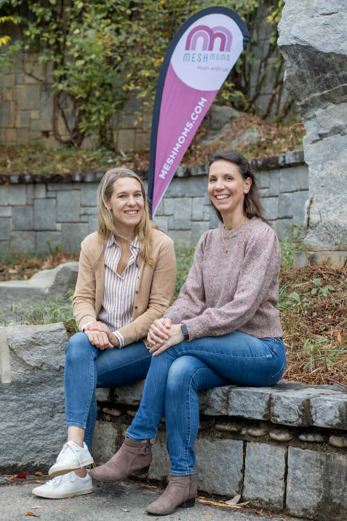 two women sitting on a stone ledge