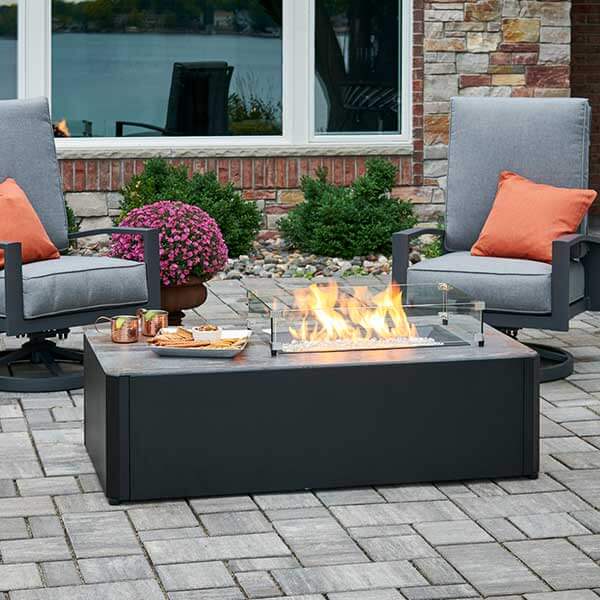 a fire pit with chairs and a glass top
