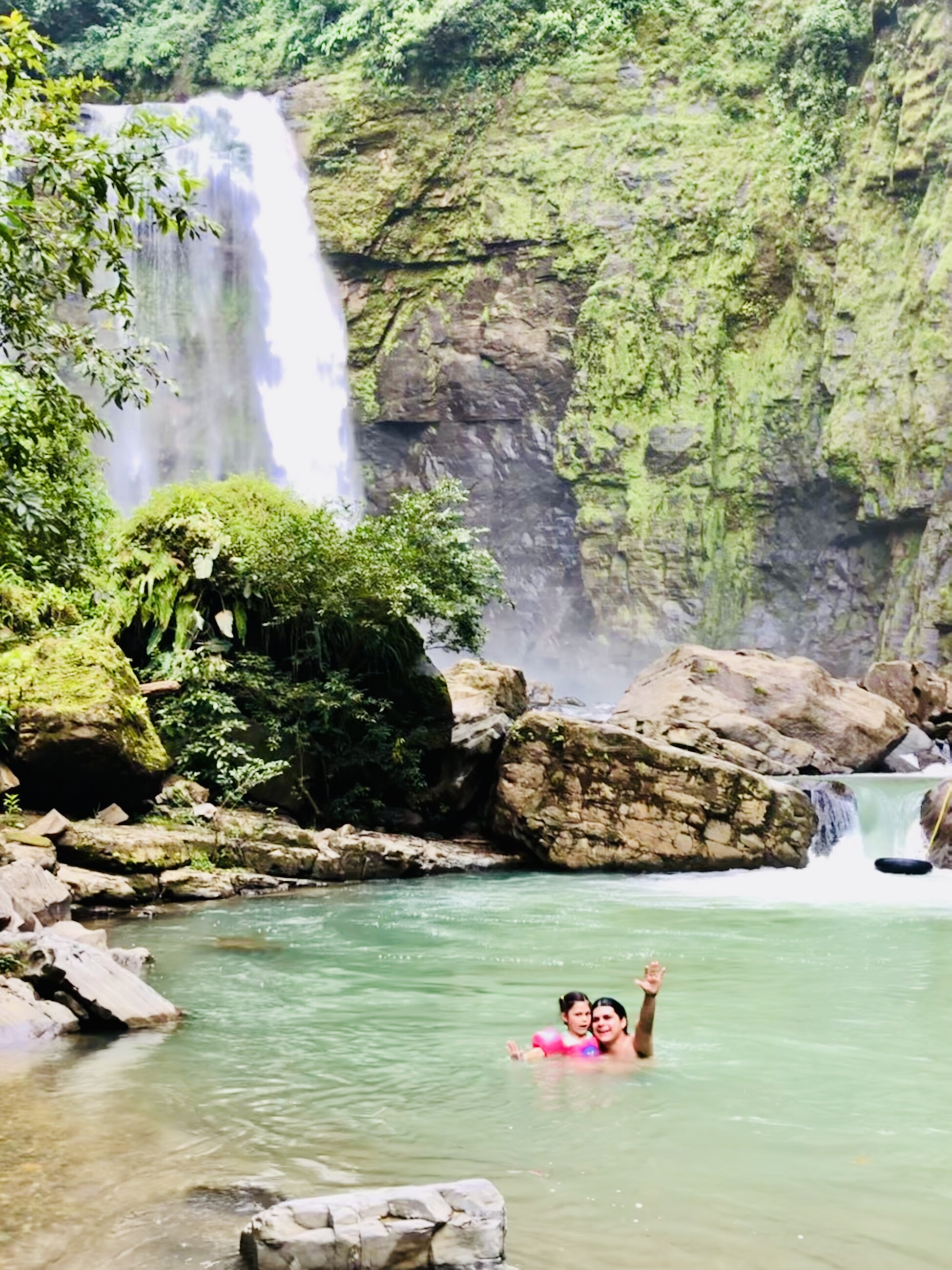a couple in a pool of water with a waterfall in the background