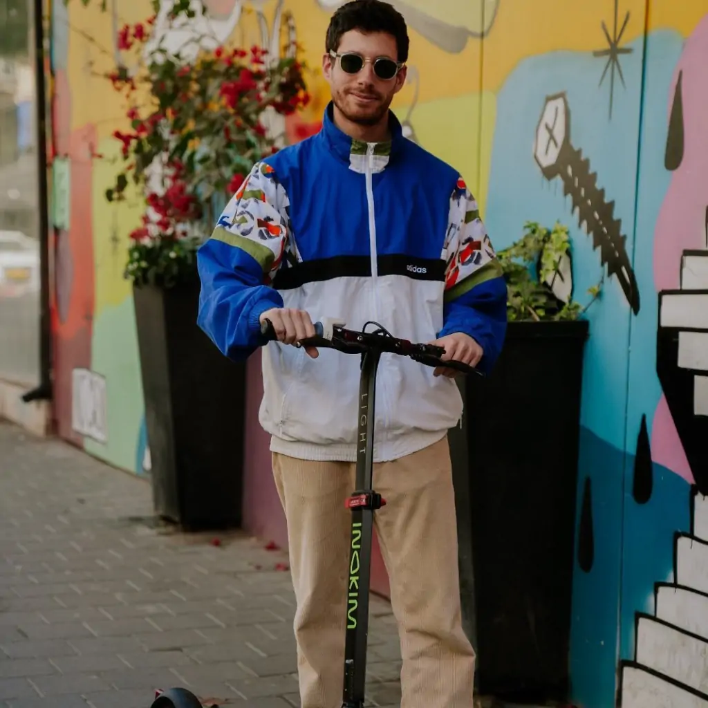 a man wearing sunglasses and a blue and white jacket with a scooter