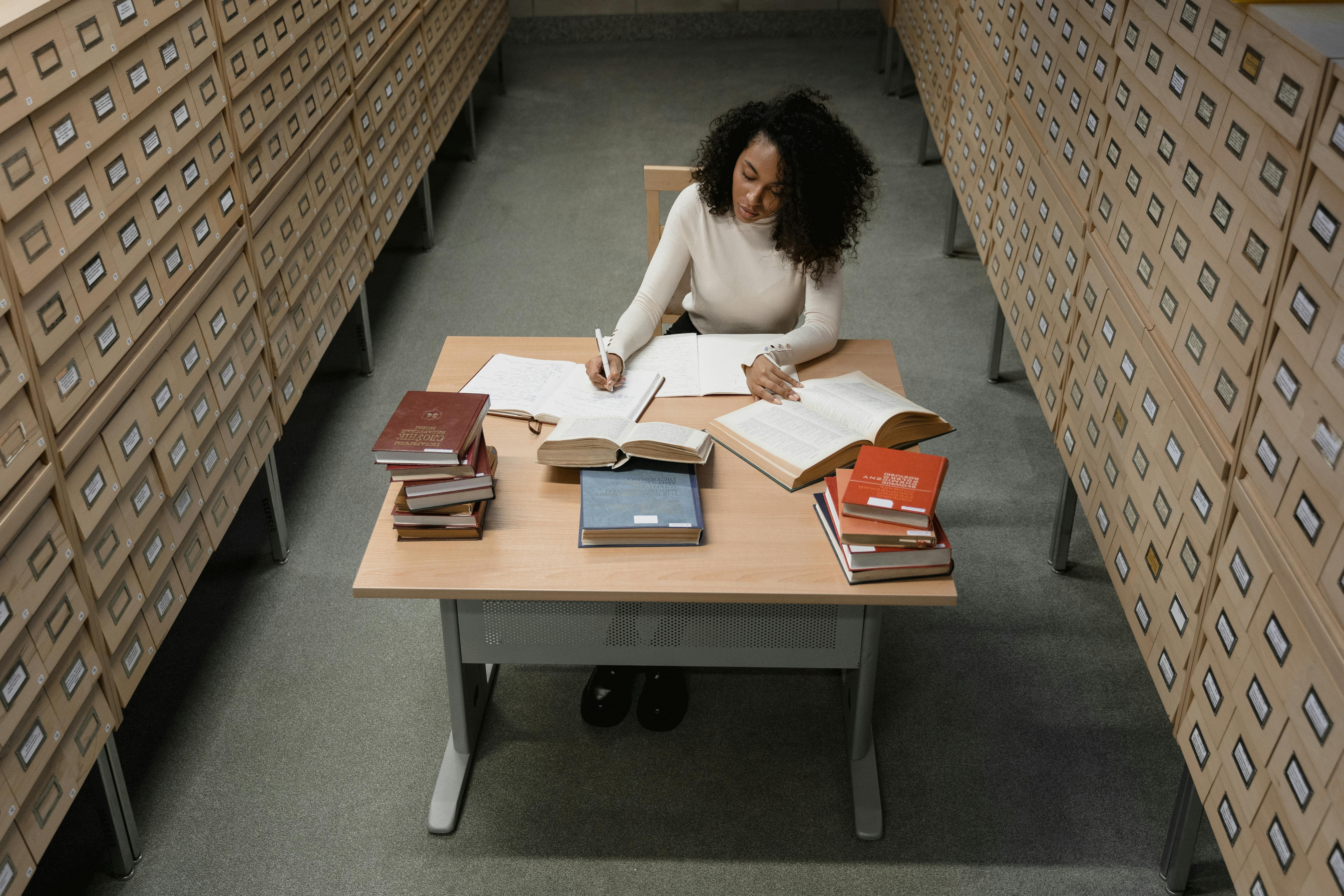 a woman sitting at a desk with books and a pen
