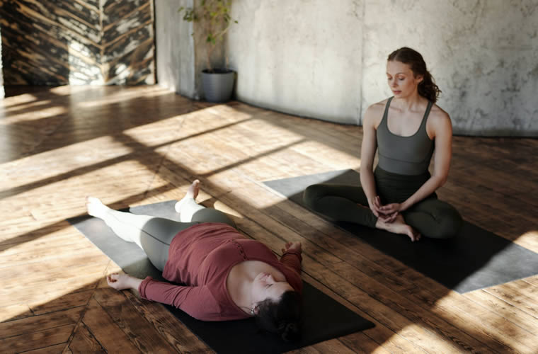 two women sitting on yoga mats
