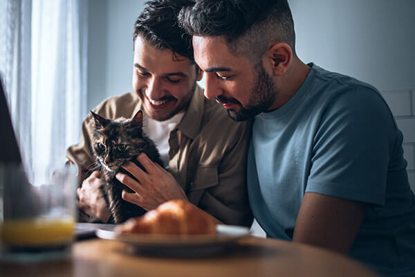 two men holding a cat