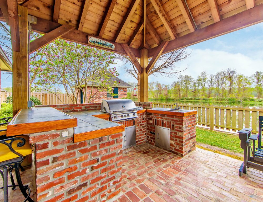 a barbecue area with a wood roof and a fence