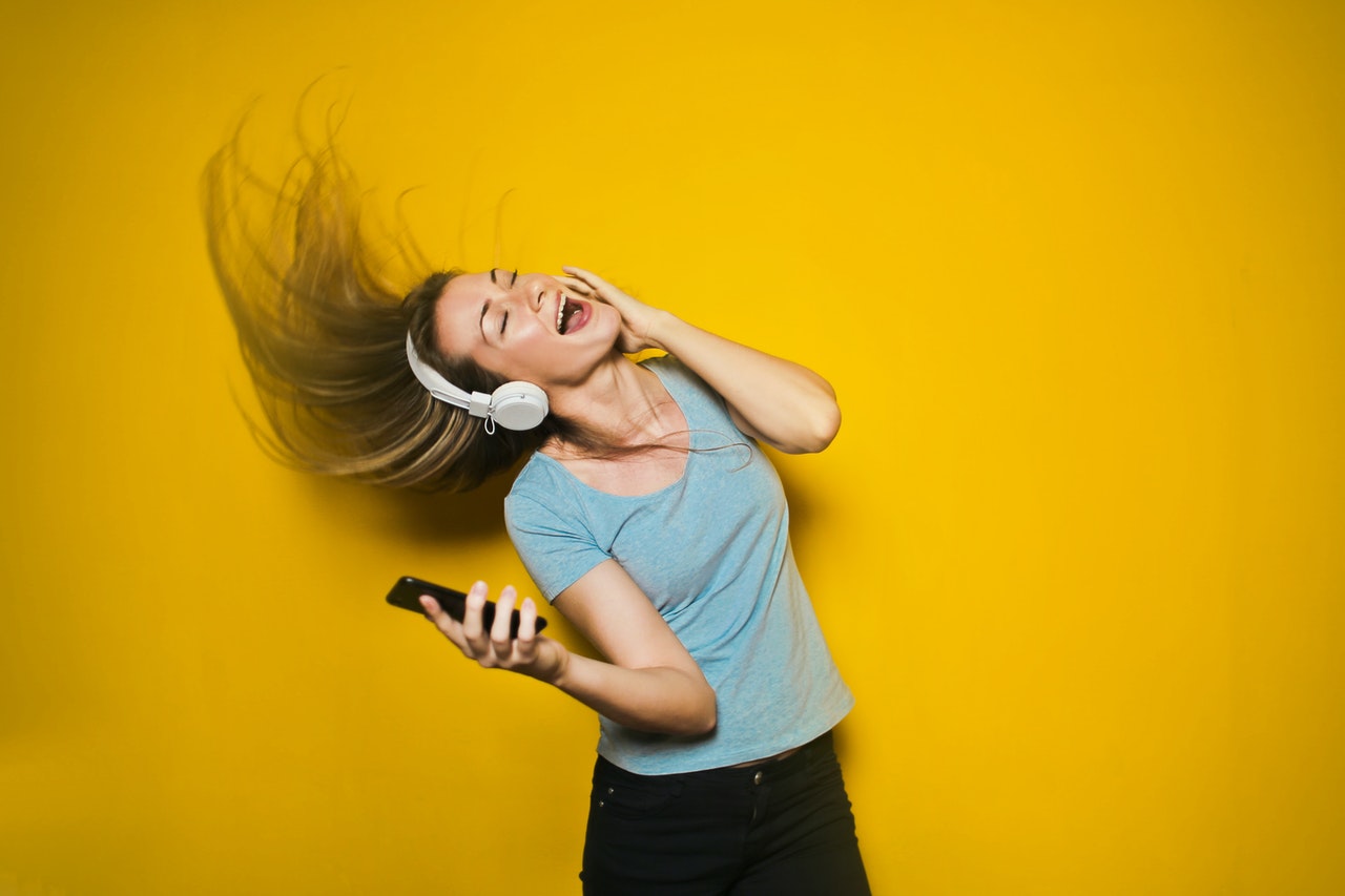 a woman wearing headphones and dancing with her hair blowing in the wind