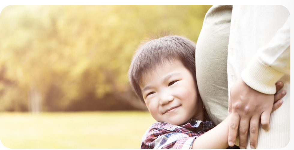 a child hugging a pregnant woman