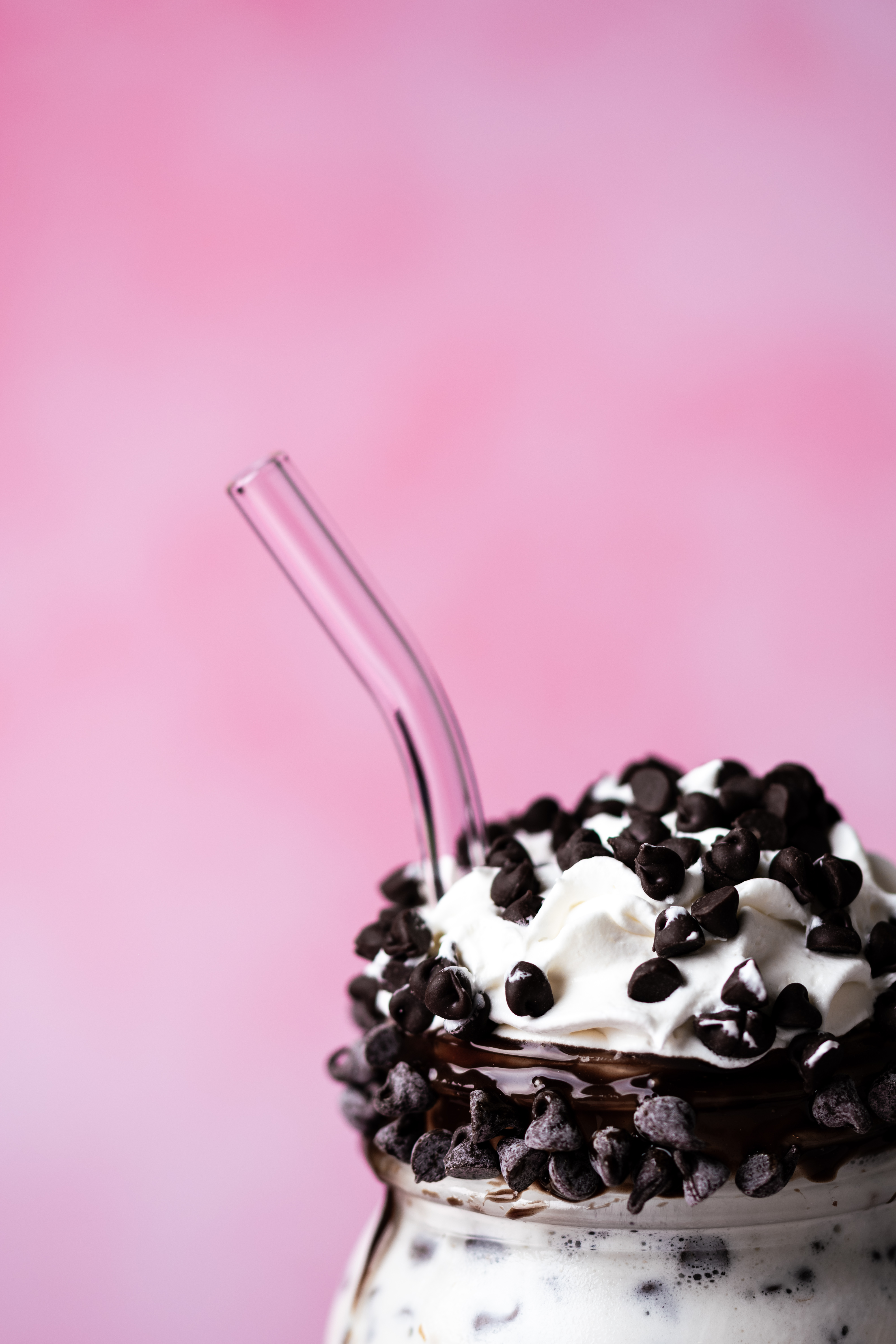 a glass cup with a straw and chocolate chips on top