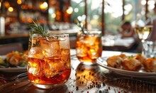 a glass of ice tea with a sprig of rosemary on a table