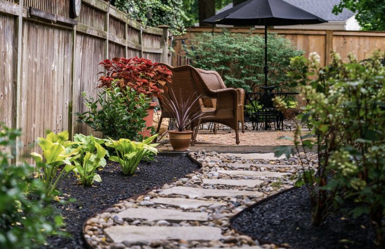 a garden with a stone path and chairs