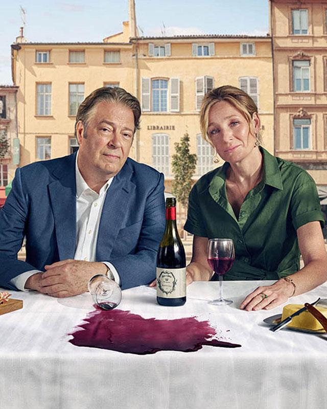 a man and woman sitting at a table with a bottle of wine