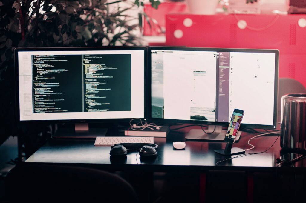 a desk with multiple monitors and a phone