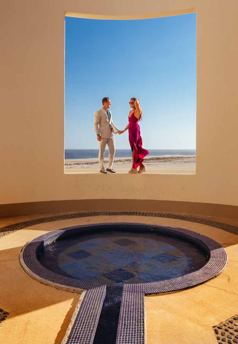 a man and woman holding hands and standing on a wall with a pool