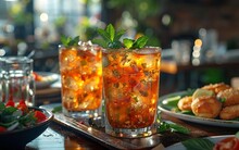 two glasses of liquid with ice and mint leaves on a tray