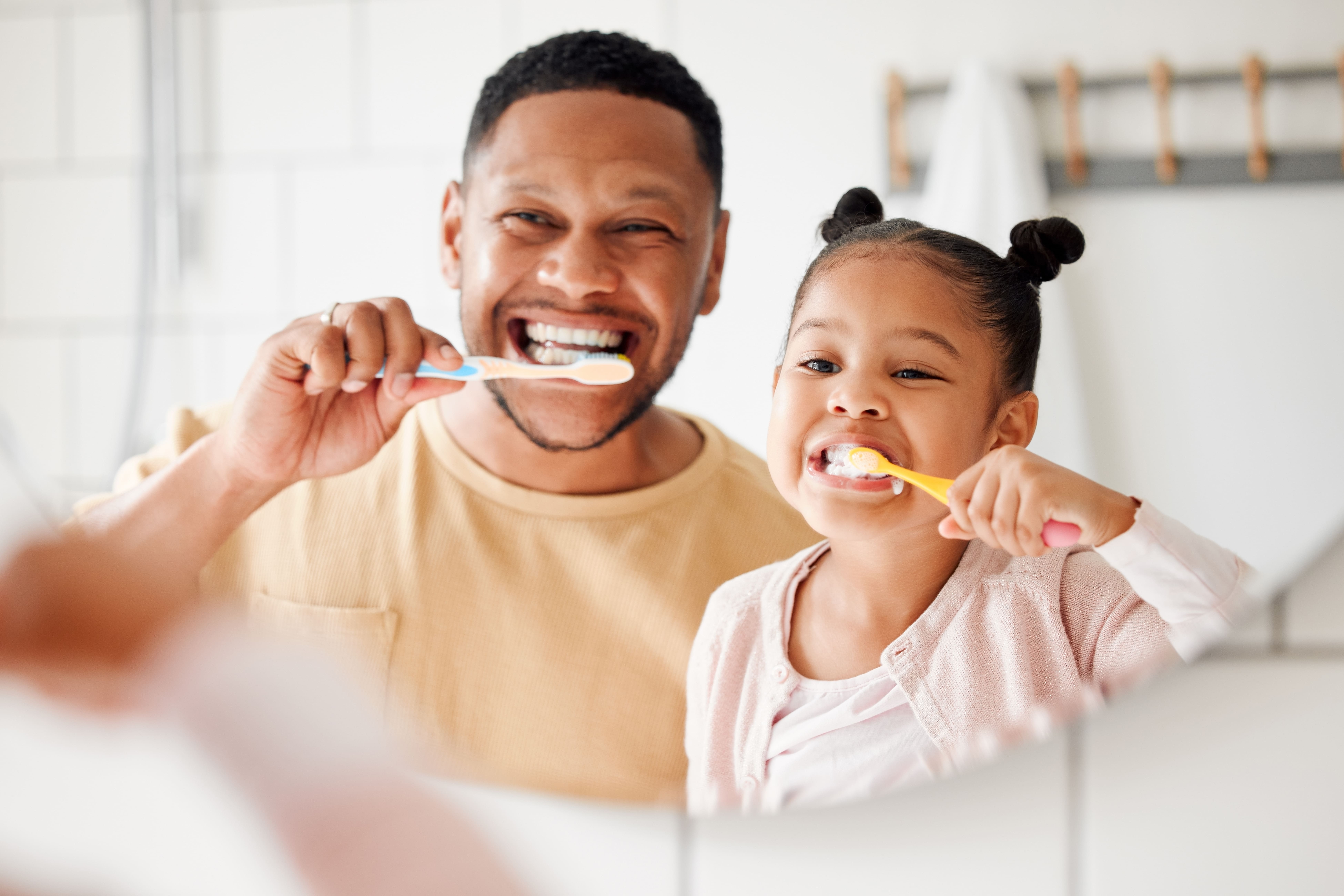 a man and a girl brushing their teeth