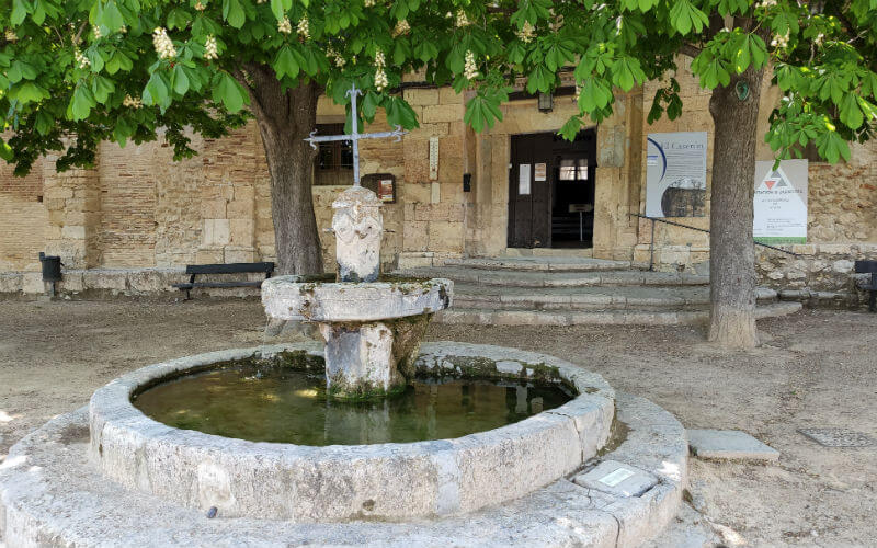 a stone fountain with a cross in the middle of a courtyard