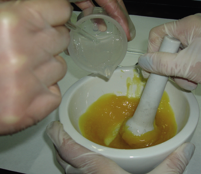 hands in gloves pouring liquid into a mortar