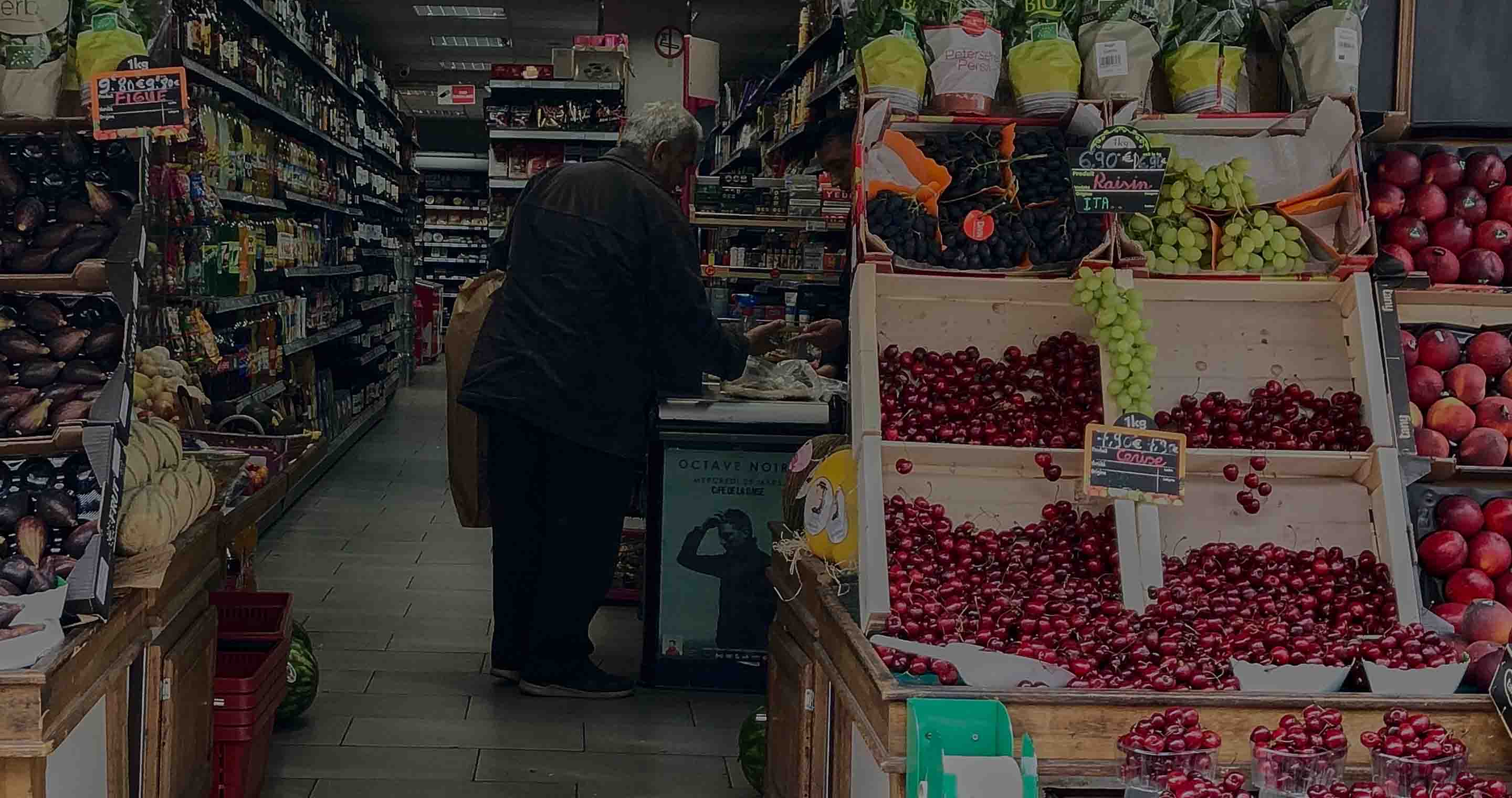 a man standing next to a counter with fruits in a store