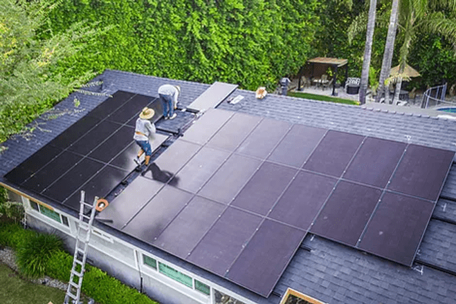 a couple of men installing solar panels on a roof