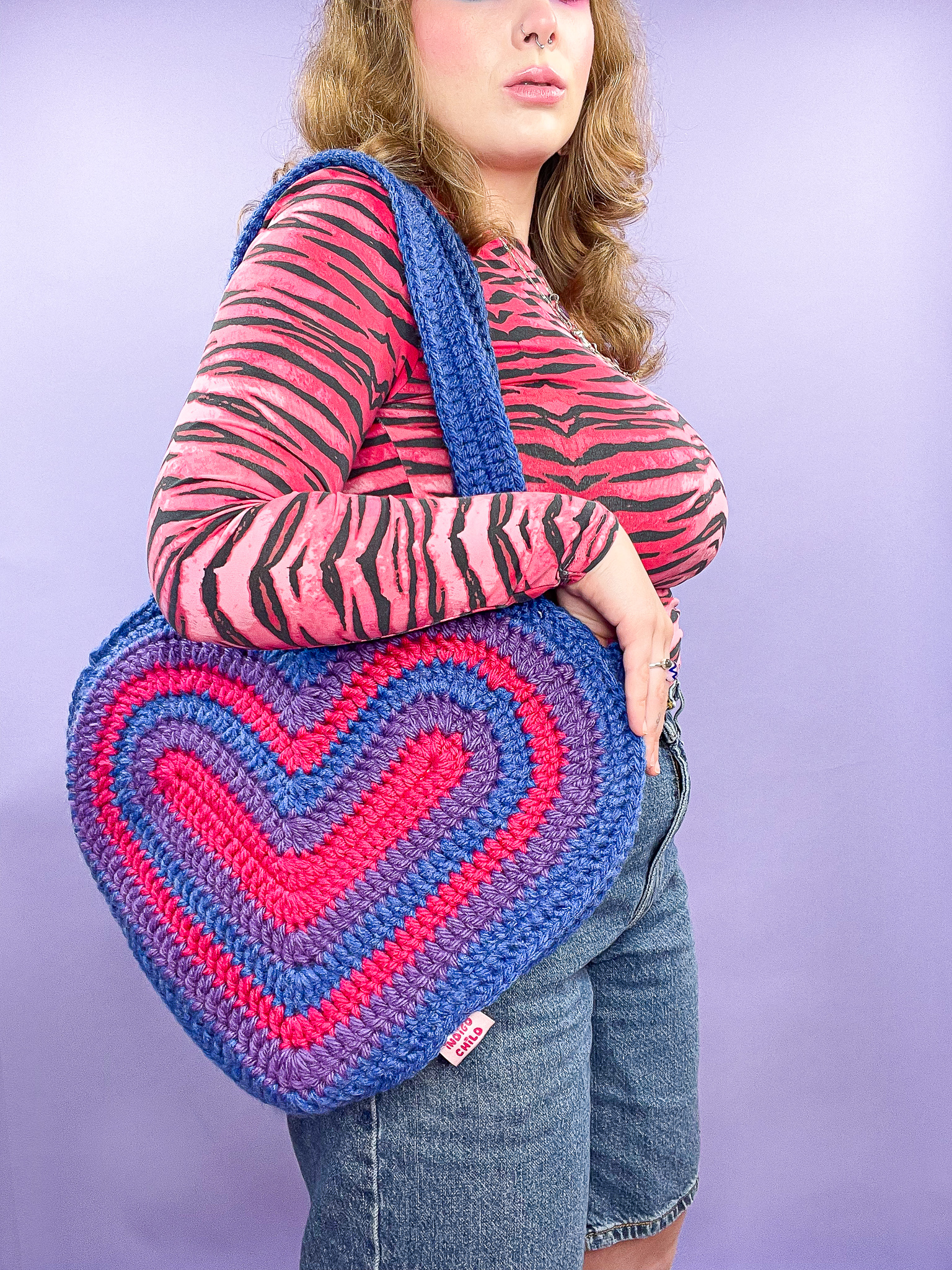 a woman holding a crochet heart bag