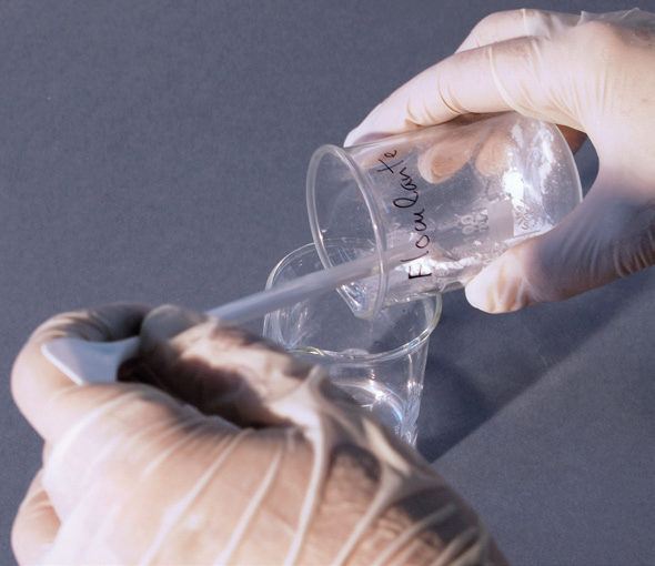 a person pouring liquid into a plastic cup