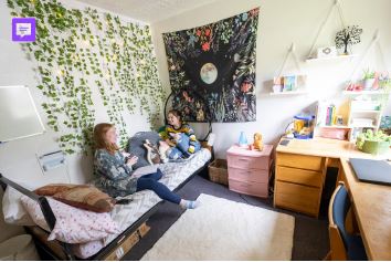 a girl and boy sitting on a bed in a room