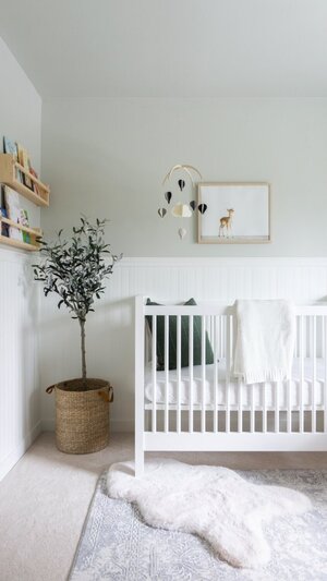 a white crib with a plant in a basket