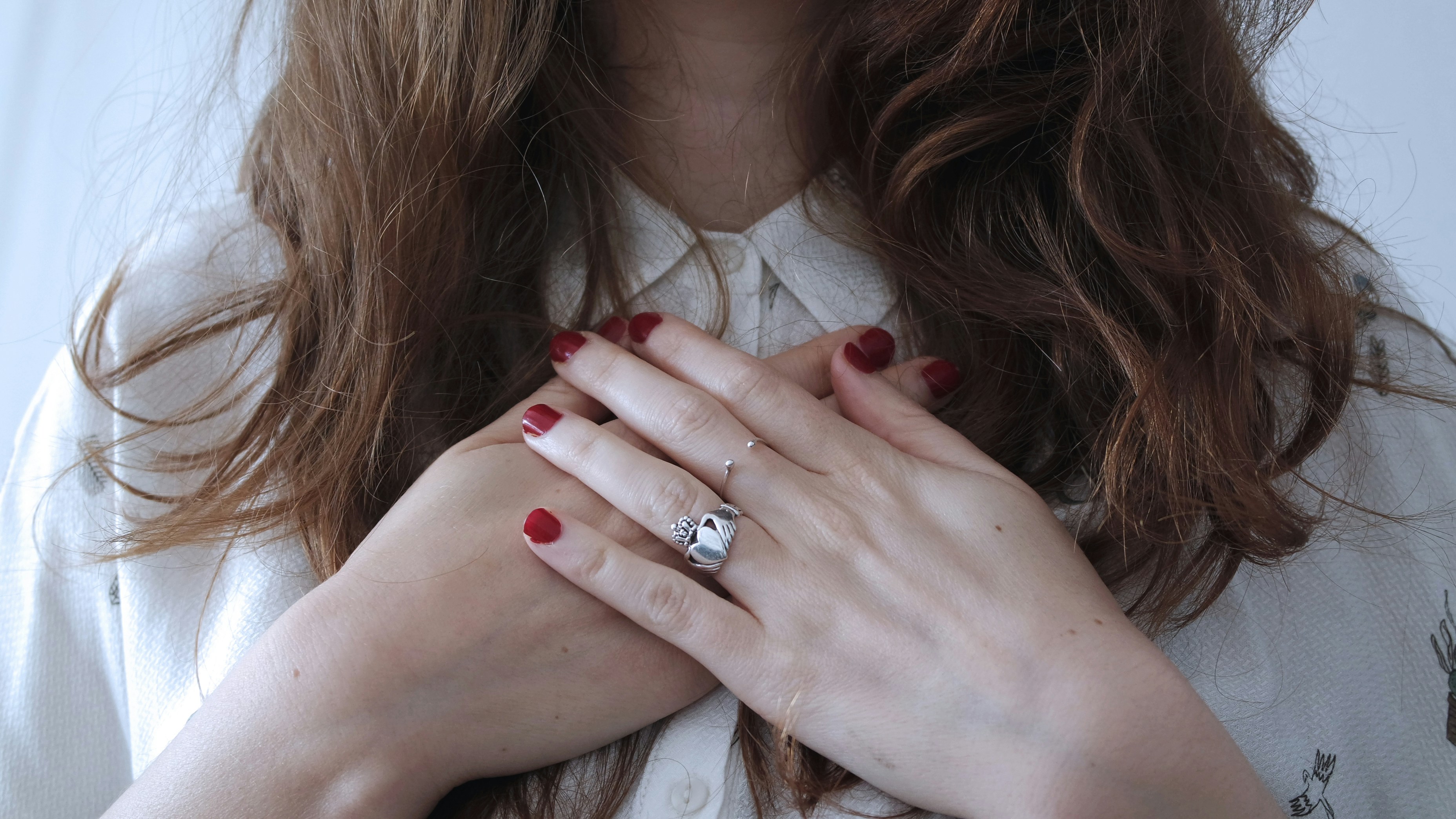 a woman with red nails and a ring on her hands