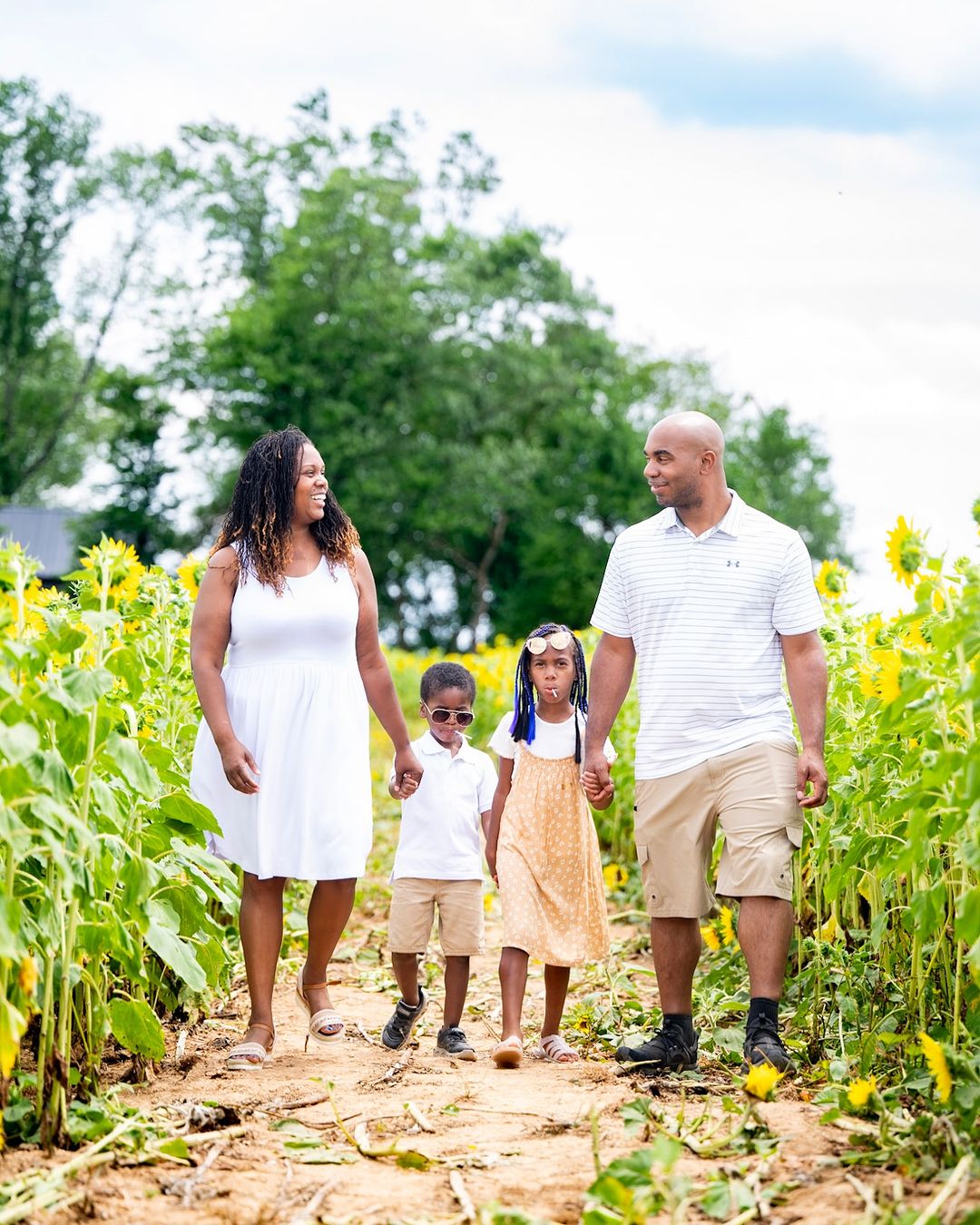 a family walking on a dirt path with sunflowers