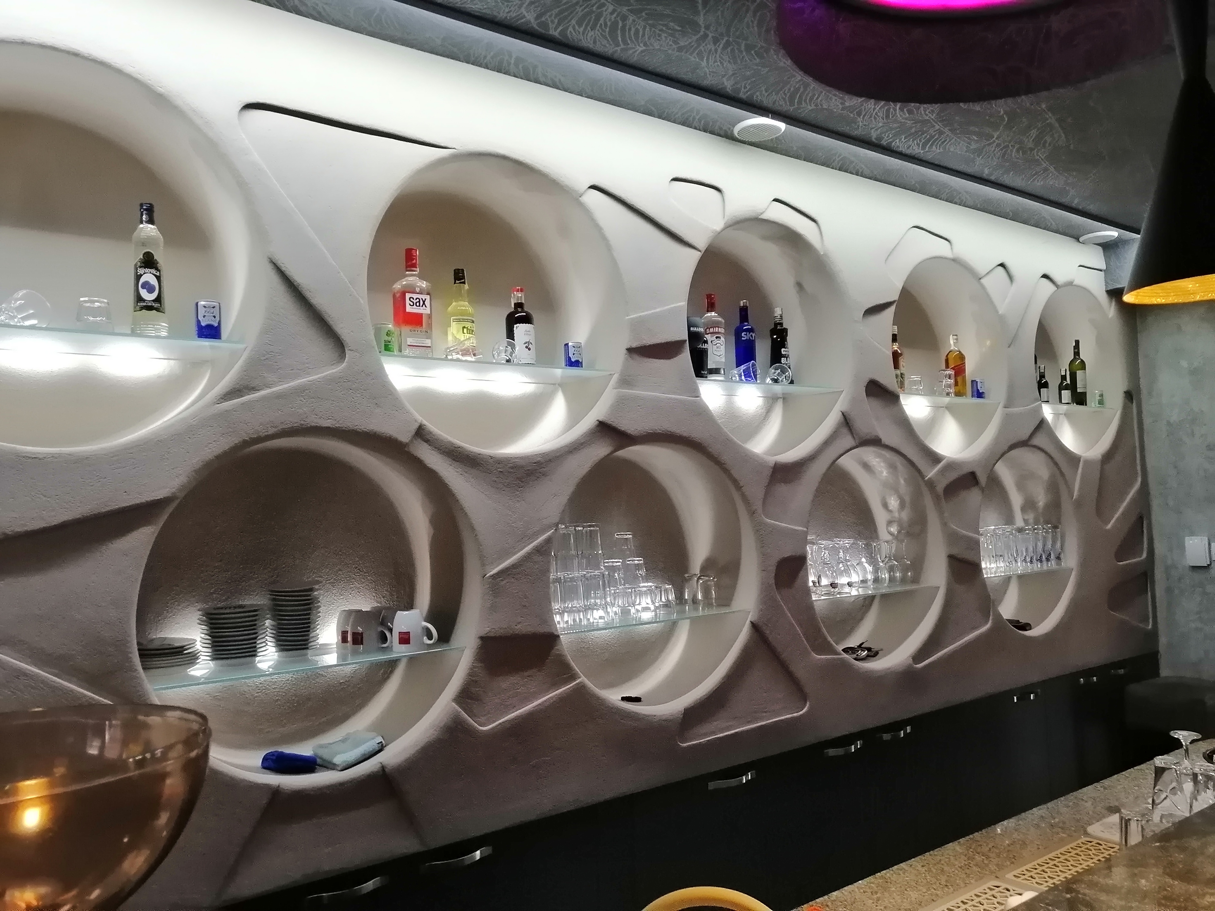 a wall with shelves of liquor bottles and glasses