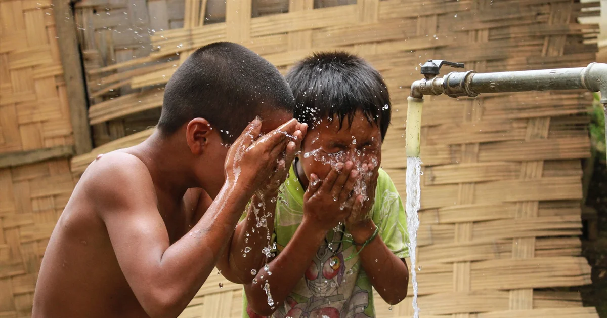 two boys washing their face with water
