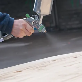 a person spraying a wood surface