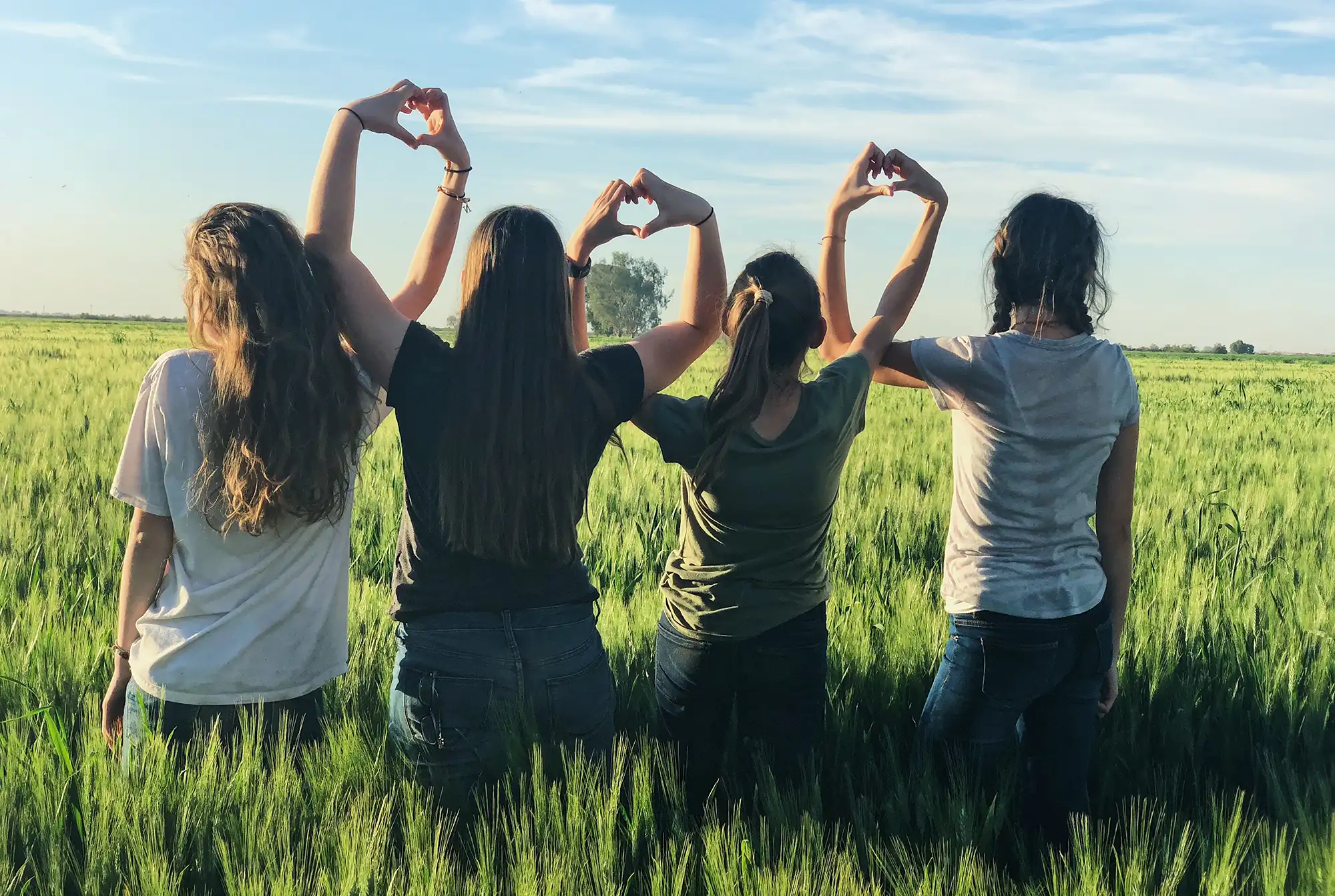 a group of girls making a heart with their hands