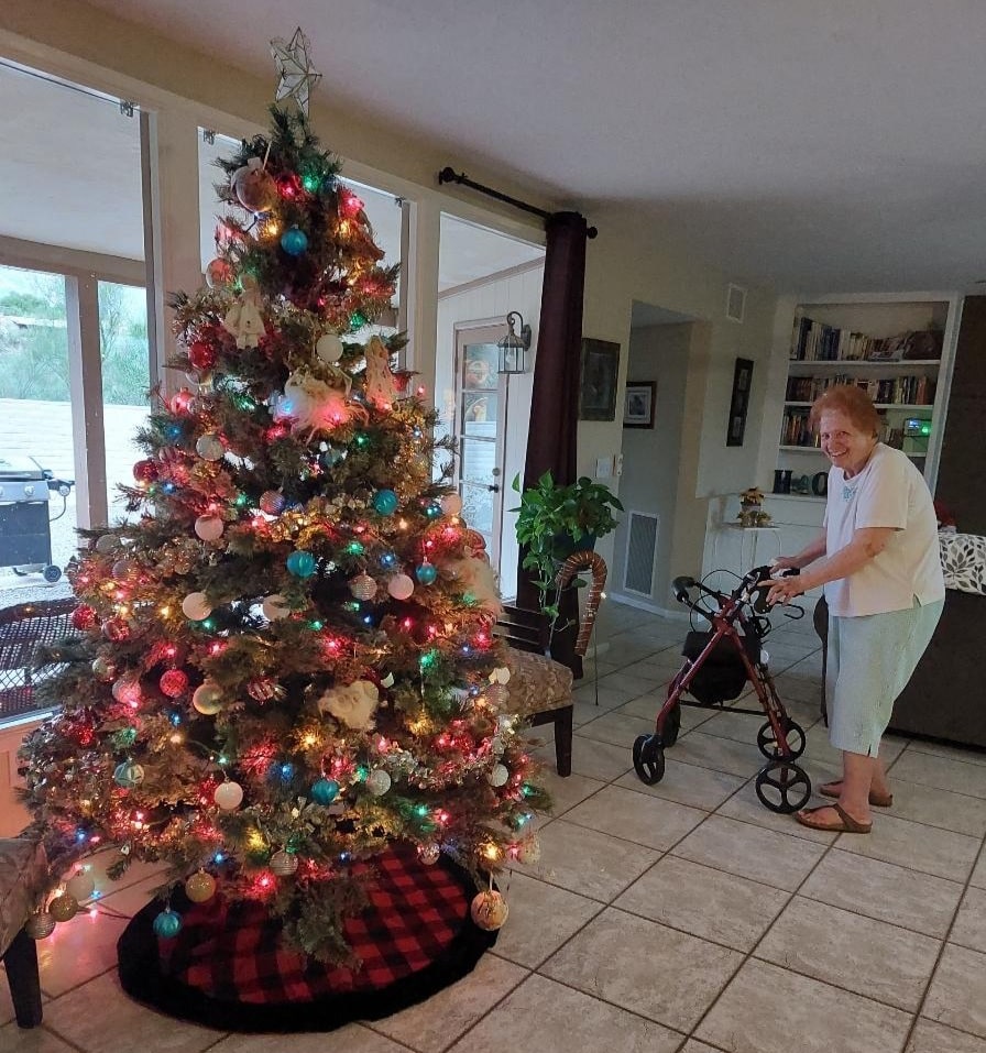 a woman standing next to a christmas tree