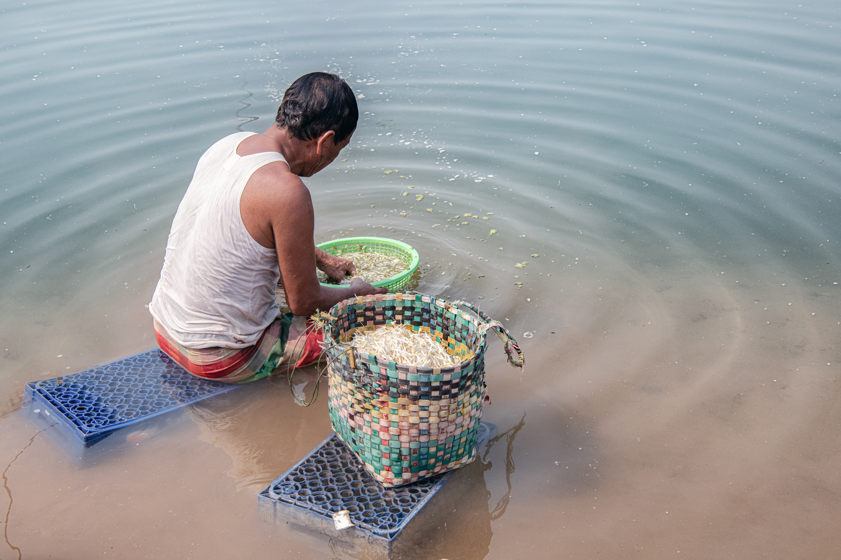 a man sitting in water with baskets of food